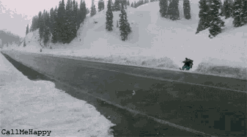 a snowboarder is doing a trick on a snowy road .