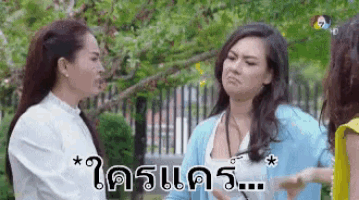 three women are standing next to each other in a park and one of them is making a funny face .