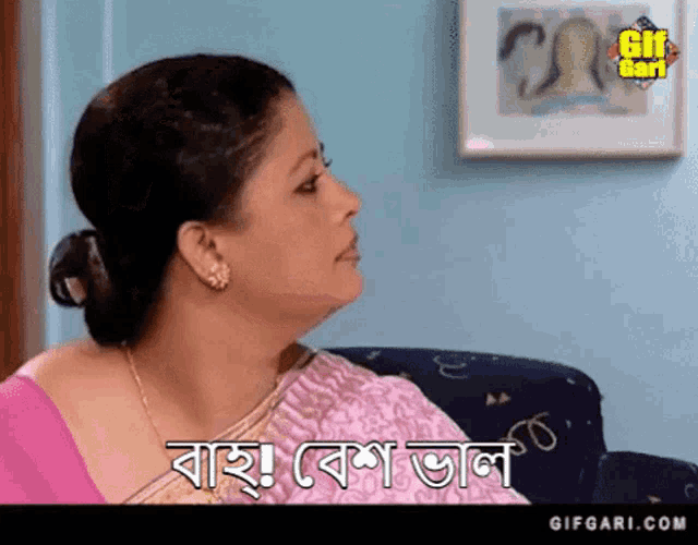 a woman in a pink saree is sitting on a couch and says " gifgari.com " on the bottom