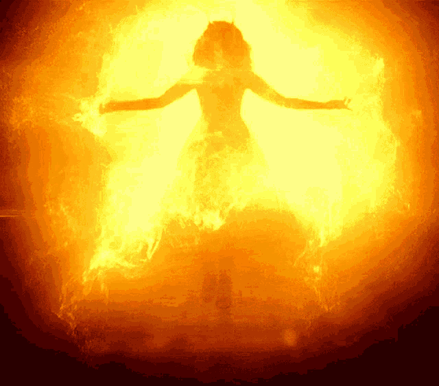 a silhouette of a woman surrounded by flames in a dark room