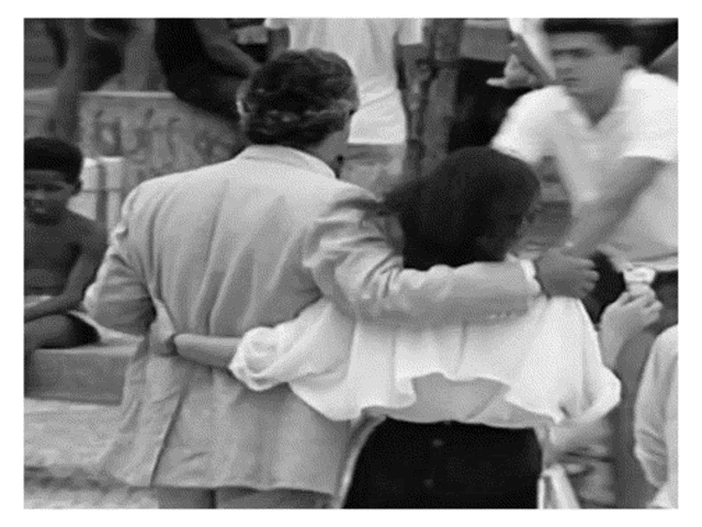 a black and white photo of a man and woman hugging in a crowd