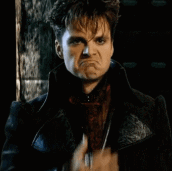 a man in a black jacket is screaming with his mouth open .