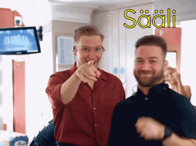 a man in a red shirt points at the camera with the word saali in yellow letters