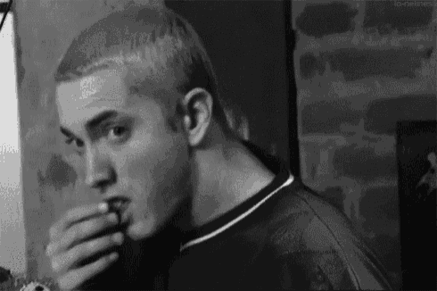 a black and white photo of a man eating a piece of pizza .