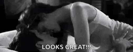 a woman is laying on top of a man on a bed and kissing him .