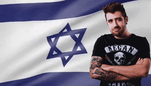 a man in a negan shirt stands in front of a israeli flag