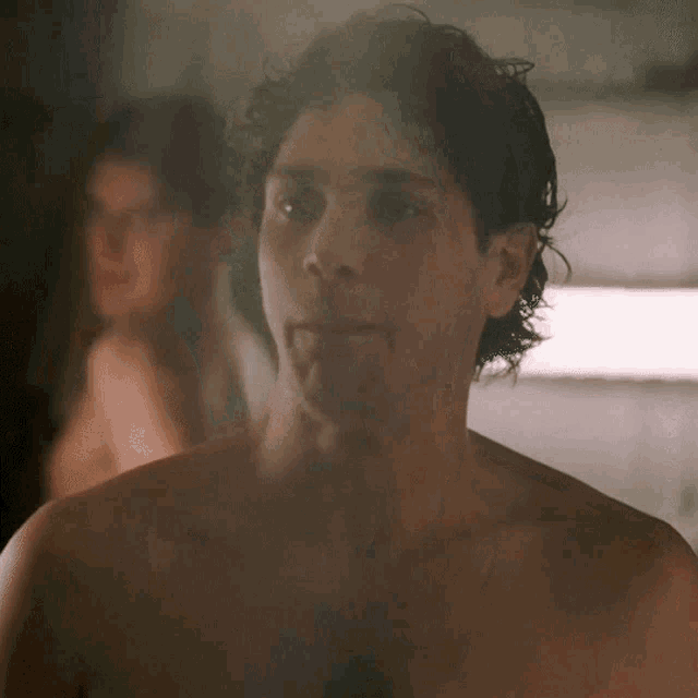 a man without a shirt looks at the camera