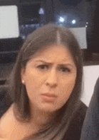 a woman is making a funny face while sitting in front of a laptop computer .