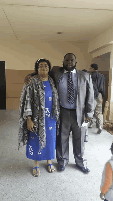 a man in a suit and tie poses with a woman in a blue dress and sandals