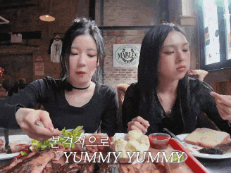 two women sitting at a table with plates of food and a sign that says marbles