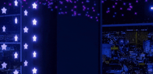 a room with a lot of lights on the wall and a window with a city in the background .