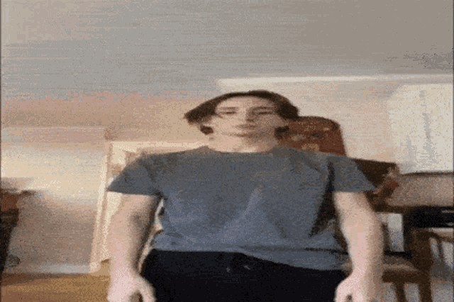a man in a grey shirt is standing in a room