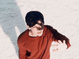 a young man wearing a red sweater is standing in the snow