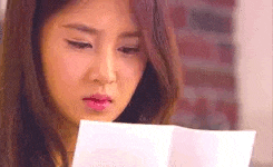a woman is holding a piece of paper in her hand and reading it .