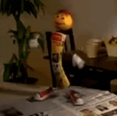 a puppet is standing on a table with a bag of chips