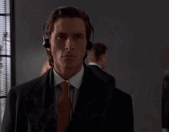 a man wearing headphones and a tie looks at the camera