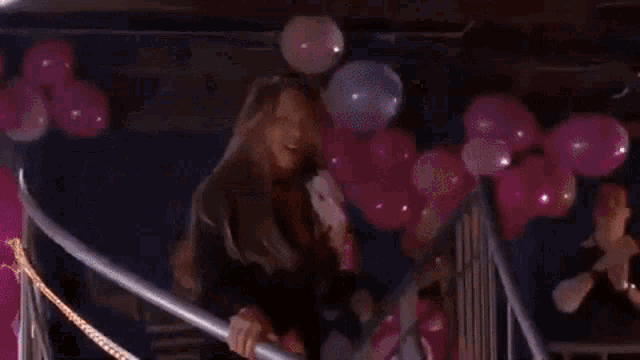 a woman singing into a microphone with balloons in the background