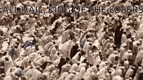 a large group of people are kneeling down in front of a sign that says all hail king of the losers .