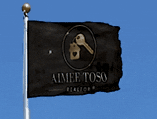 a black aimee toso realtor flag is flying in the wind
