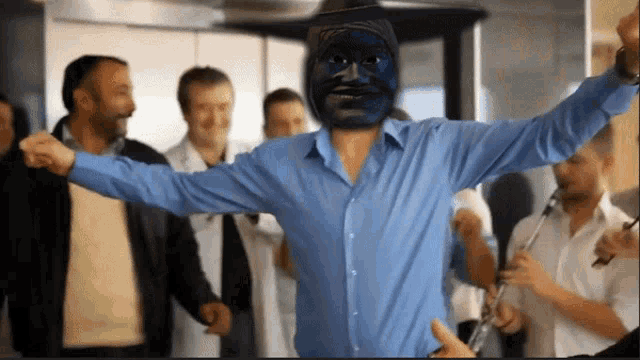 a man with a blue mask on his face is dancing in a crowd