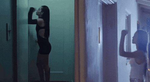 a woman in a black dress is standing next to a door