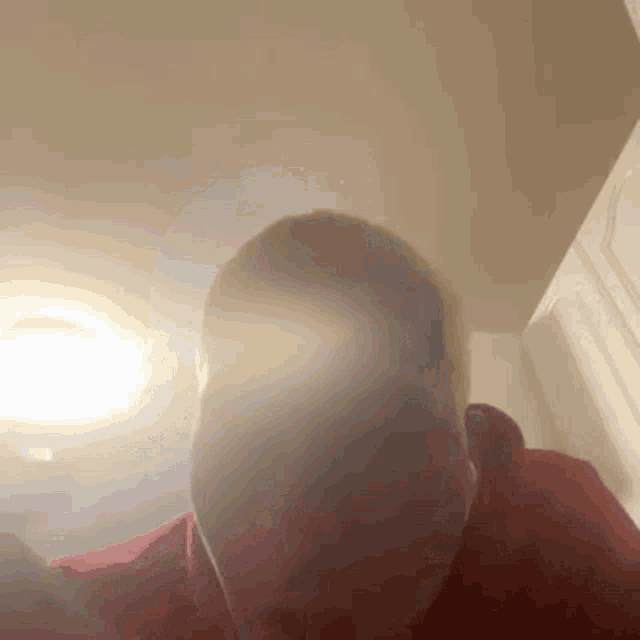 a man in a red shirt is looking up at the camera