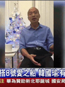 a man sitting in front of a christmas tree with chinese writing
