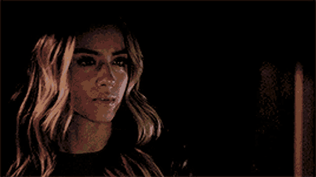 a close up of a woman 's face in a dark room looking at the camera .