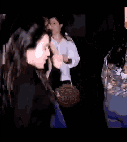 a woman in a black sweater is dancing in front of a sign that says ' india '