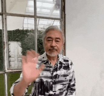 a man with a beard is waving his hand in front of a large window .