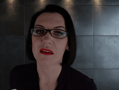 a woman wearing glasses and red lipstick is making a face