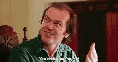 a man in a green shirt is sitting in a chair talking to another man .