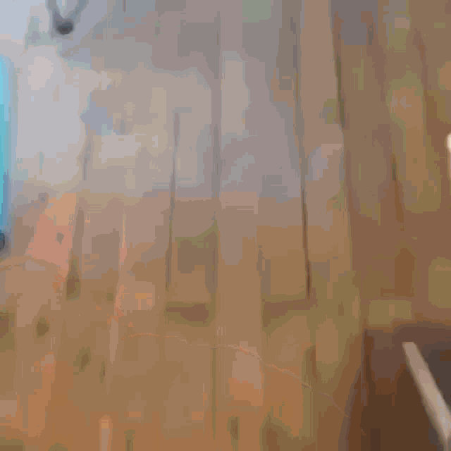 a blurred image of a wooden floor with a chair in the background
