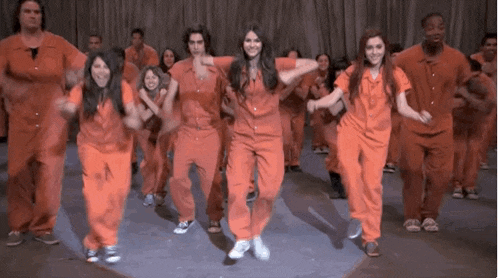 a group of people in orange jumpsuits are dancing on stage