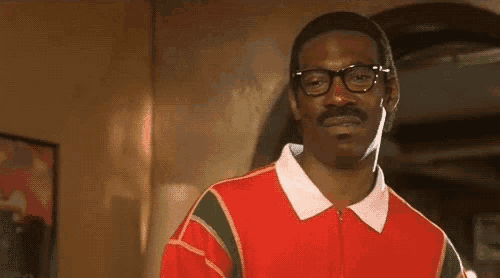 a man with glasses and a mustache is wearing a red shirt and a white collar .