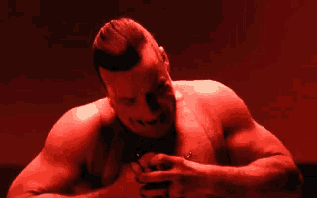 a shirtless man is holding a bloody object in his hands .