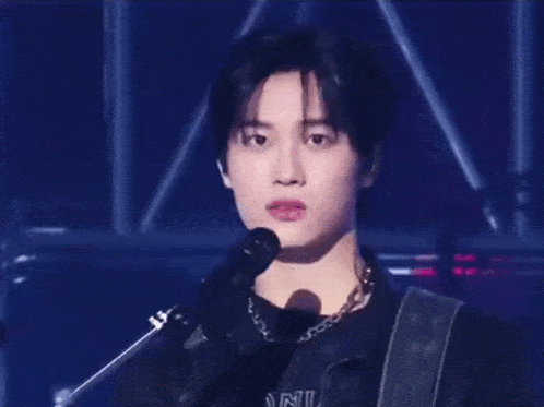 a young man is standing in front of a microphone on a stage and smiling .