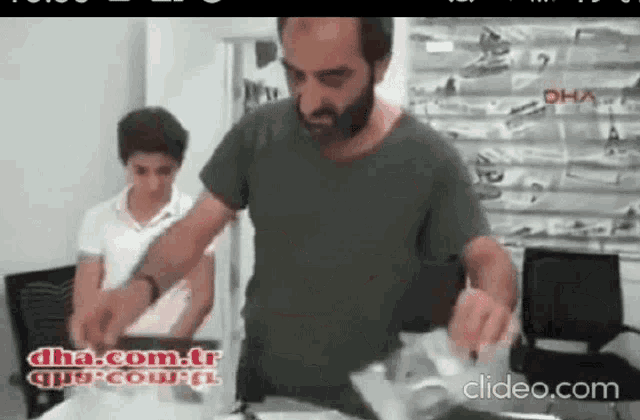 a man with a beard is standing next to a boy in a room with the words dha.com.tr written on the bottom