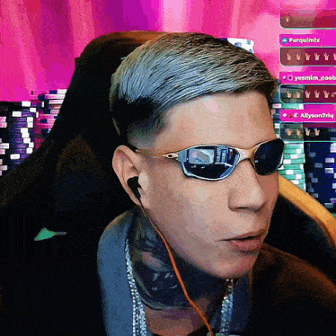 a man wearing sunglasses is sitting in front of a pink background