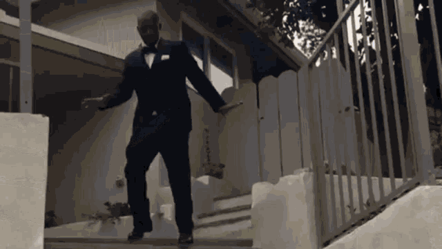 a man in a tuxedo and bow tie is dancing on a set of stairs