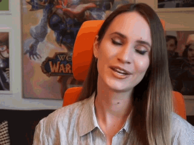 a woman sits in front of a world of warcraft poster