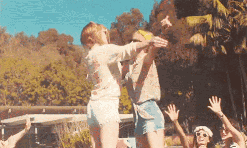 a group of people are dancing in a pool while a man throws a frisbee .
