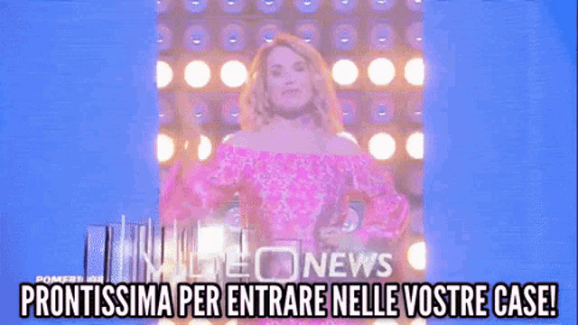a woman in a pink dress is standing in front of a wall of speakers and says prontissima per entrare nelle vostre