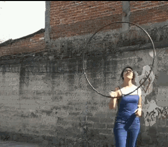 a woman in a blue tank top is holding a hula hoop