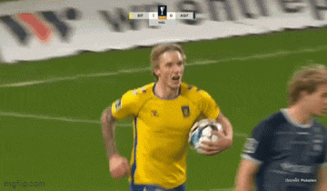 a man in a yellow jersey is running with a soccer ball on a field