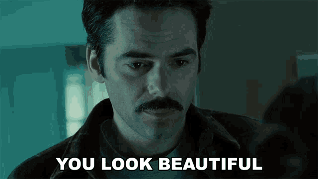 a man with a mustache says " you look beautiful " to another man
