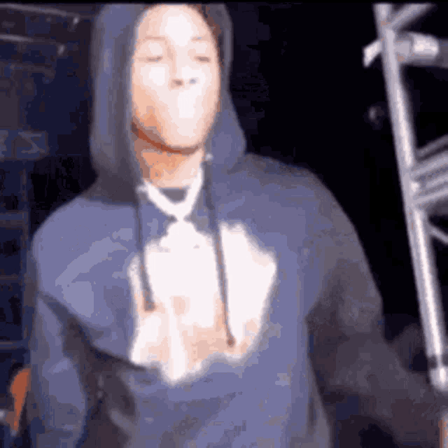 a man in a blue hoodie is standing in the dark .