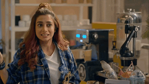 a woman in a plaid shirt is standing in front of a coffee maker