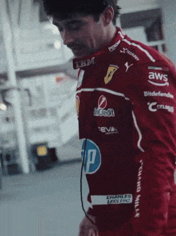 a man wearing a red racing jacket with sponsors such as ibm and aws on his sleeves