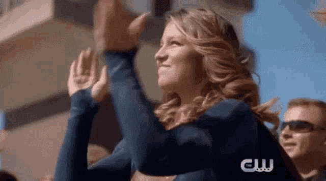 a woman in a superman costume is giving a high five to a crowd of people .